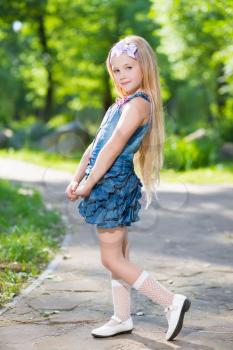 Adorable blond girl posing in jeans dress outdoors