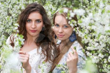 Two pretty caucasian women posing in blooming garden