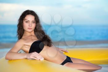 Young charming lady wearing black swimsuit posing in the yellow pool