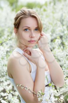 Portrait  of beautiful young blond woman in blooming garden