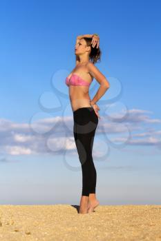 Pretty slim lady in tight black leggings posing on the beach
