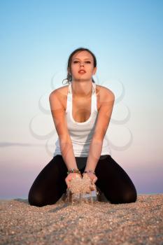 Young woman in white t-shirt playing with sand on the beach
