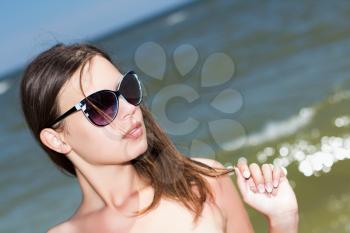 Portrait of pretty woman in sunglasses posing on the beach
