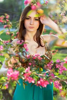 Portrait of young alluring lady posing behind the flowering tree