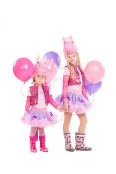 Two little girls posing in pink pony suit. Isolated on white