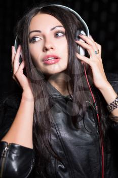 Portrait of young brunette posing with headphones. Isolated on black