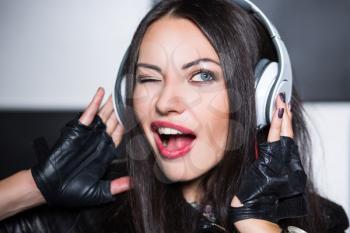 Portrait of young sexy brunette listening to the music and winking