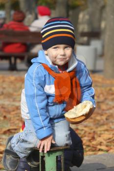 Royalty Free Photo of a Little Boy Eating Bread in a Park