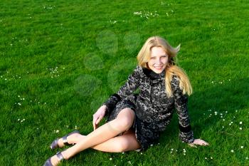 Happy girl sits on a blooming spring meadow in the early morning