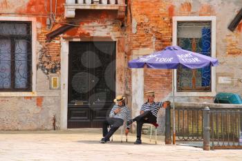 VENICE, ITALY - MAY 06, 2014: Two gondoliers on the docks awaiting tourists in Venice, Italy