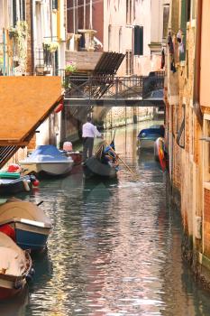 VENICE, ITALY - MAY 06, 2014: Gondolier sails with tourists sitting in a gondola down the narrow channel in Venice, Italy 