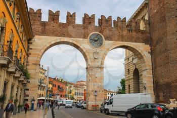VERONA, ITALY - MAY 7, 2014:  People and vehicles near the medieval city gates on Portoni della Bra. Verona, Italy 