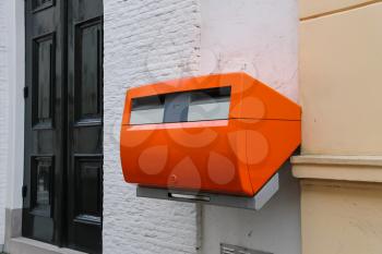 Orange mailbox on the wall of city building