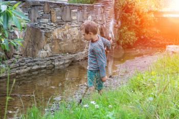 Small boy near narrow creek in city park