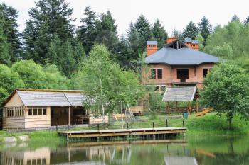 Modern cottage and a gazebo on shore of lake in Ukrainian Carpathians