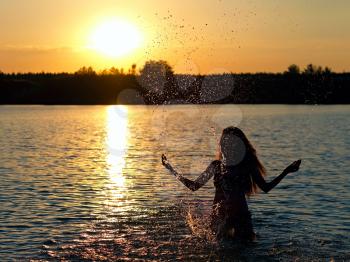 girl standing in the lake water in the rays of the setting sun