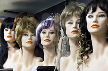 Several female mannequins with wigs on the shelf
