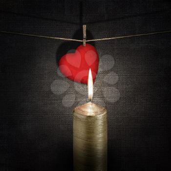 burning candle and red paper heart on a rope over vintage embossed dark backgrounds