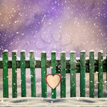 snow-covered wooden fence with  paper heart