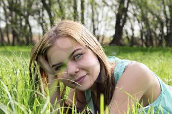Young sensual smiling blonde lying on the grass in the sunlight