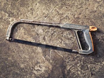 old hacksaw on concrete grungy background