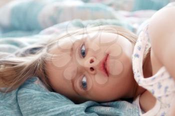 Beautiful little girl in the morning lying in bed