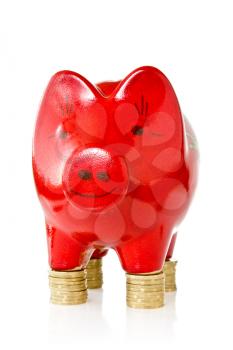 Red piggy bank standing on coins stacks