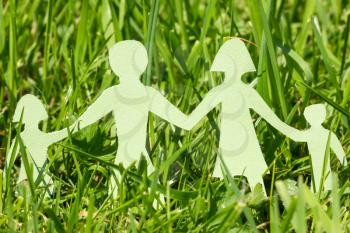 Paper family on  green grass in a bright day