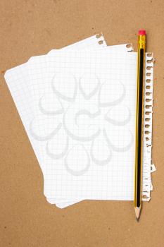Notebook sheet and pencil on a brown paper background 