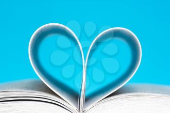 Book folded into a heart shape over a blue background