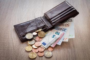 Open wallet with euro currency on the wooden table