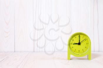 Green alarm clock on wood background. With copy-space for text