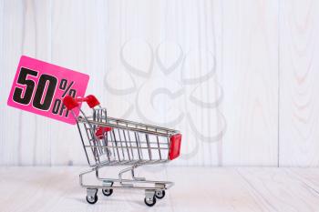 Shopping cart with tag of discount or sale,on the wooden background with copy space 
