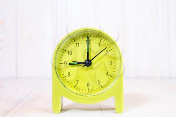 Green alarm clock on the wood background