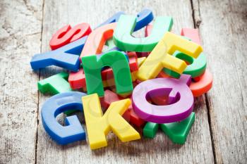 Pile of colorful plastic letters on wooden background
