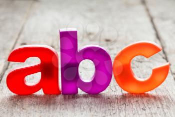ABC spelling from plastic letters on wooden background