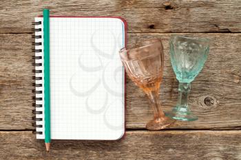 Two wine glasses and blank notebook for menu or cocktail recipes