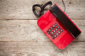 Vintage red phone on rustic wooden boards. Top view with copy-space.