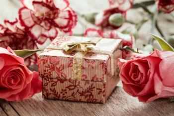 Flowers and gift box on a wooden background