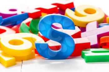 Blue letter S in a front of other colorful plastic letters. 