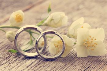 Wedding rings with wild flower on wooden background