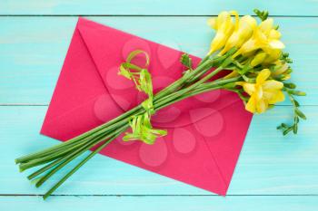  Yellow feesia flowers and red envelope,top view on wooden background