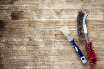 Paintbrush and wire brush on the old wooden background with copy-space