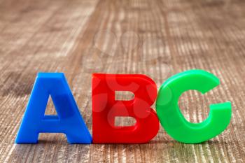   ABC spelling  of colorful plastic letters on wooden background