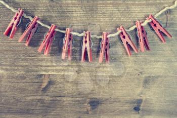 Old clothespins on rope on a wooden table or board. Filtered image.