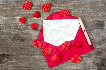 Love letter with red hearts on the wooden background