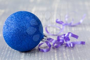 Blue bauble with ribbon on wooden background