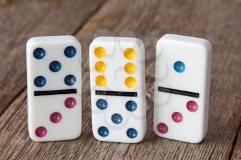 Three dominoes standing on a wooden background