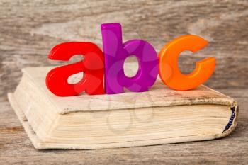 ABC spelling and old book on wooden background
