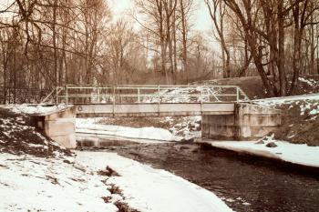 Winter creek with concrete bridge and snow covered landscape